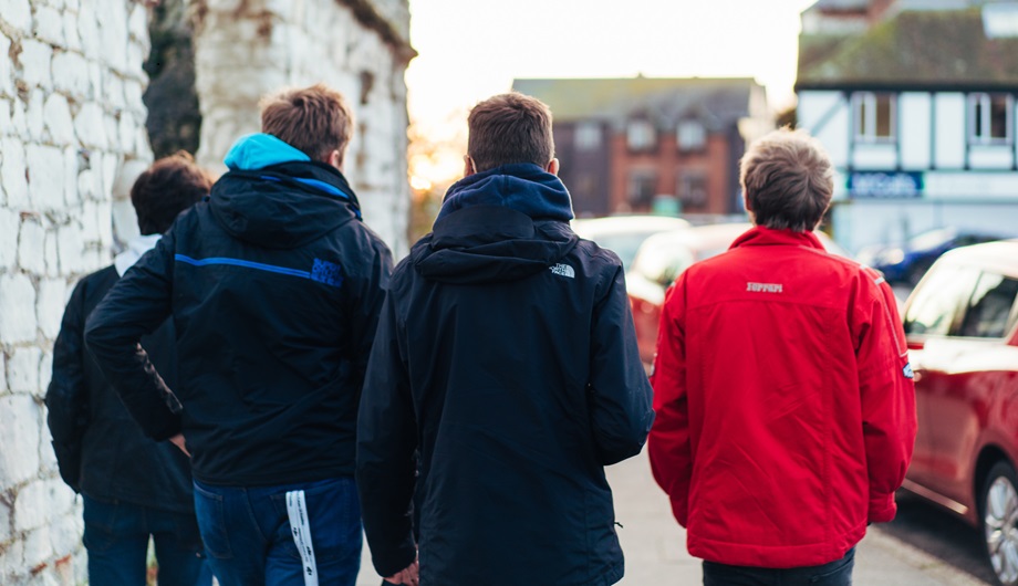 A group of four boys walking away down a street