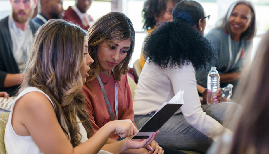 Two women talking amongst a group of trainees.