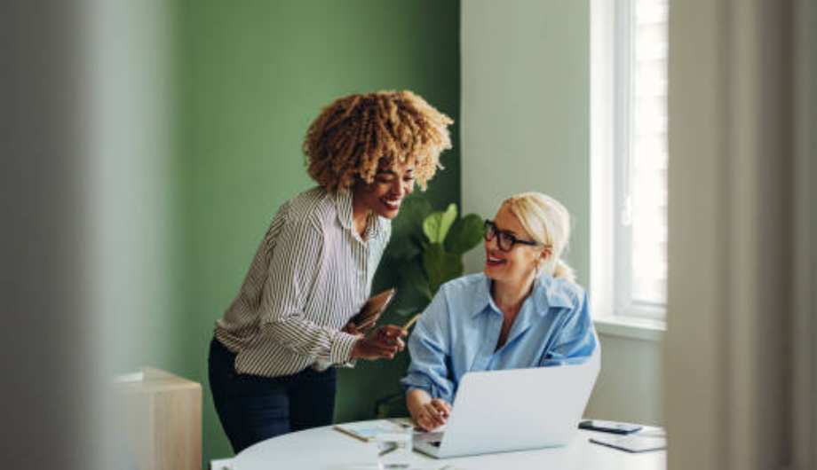Two women discussing something over a laptop.