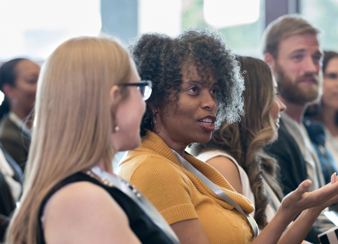 A group of people sat in a room, focus on one women who is speaking.