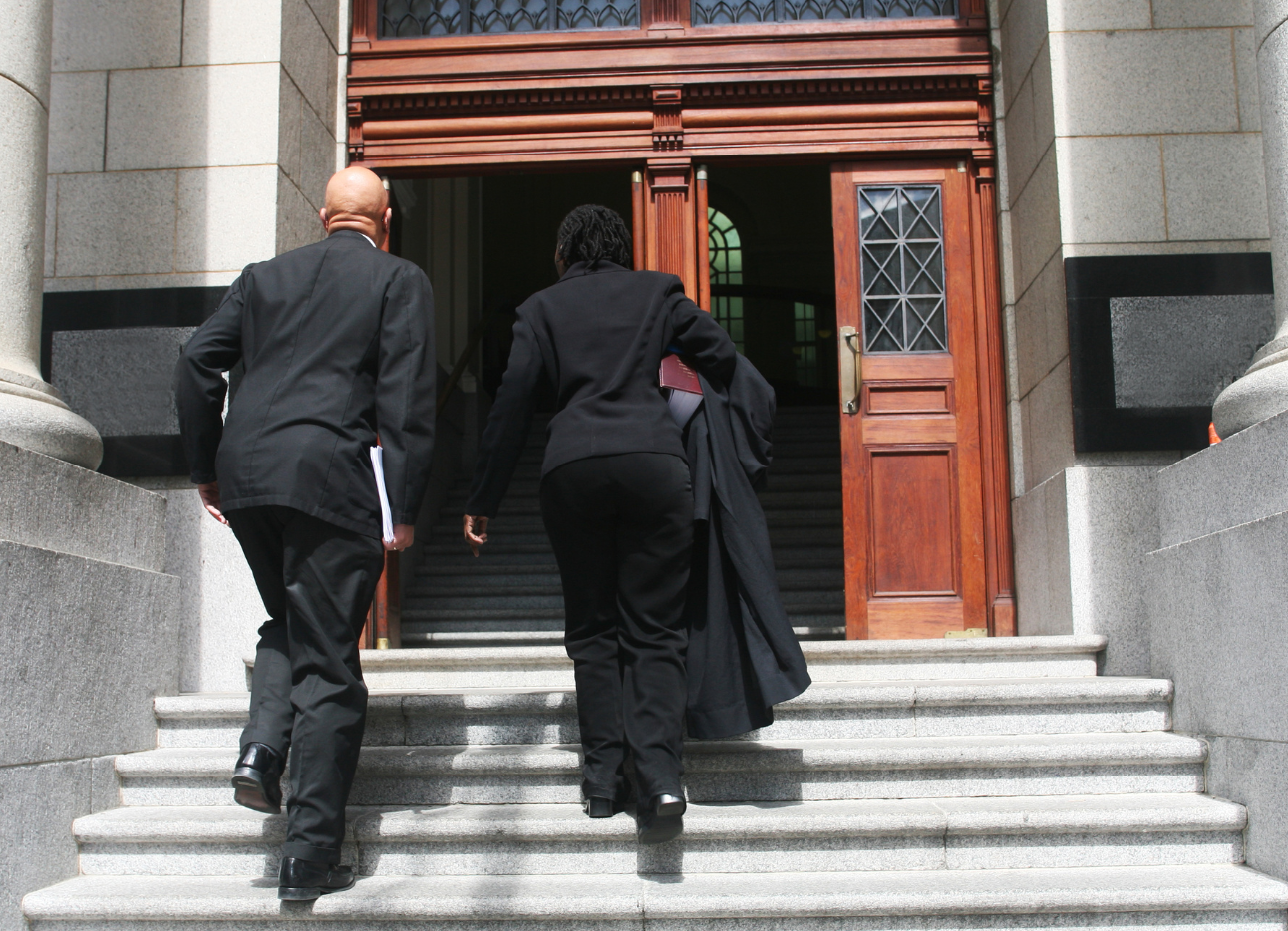 Two people in suits walking towards a court door.