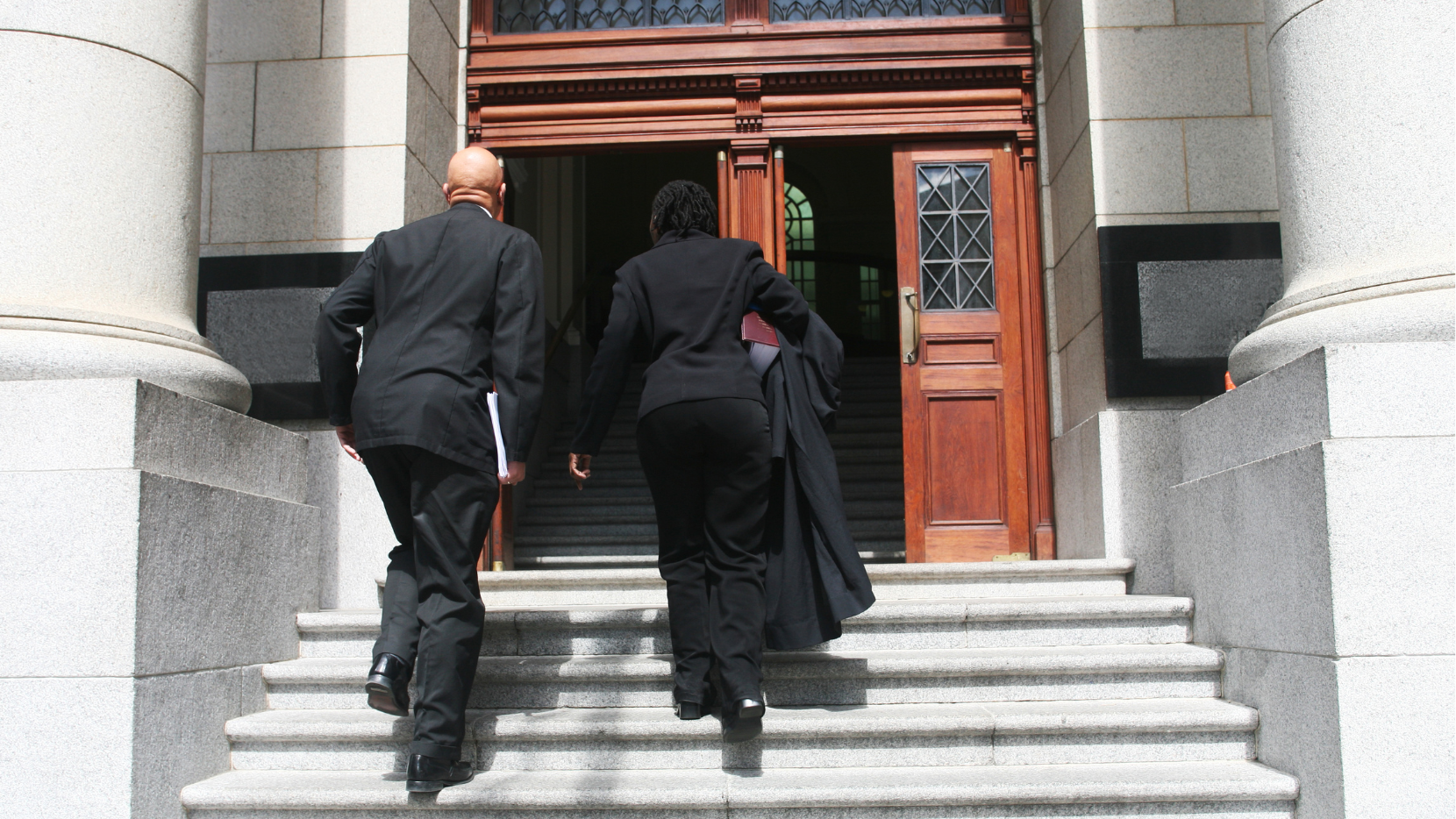 Two people in suits walking towards a court door.