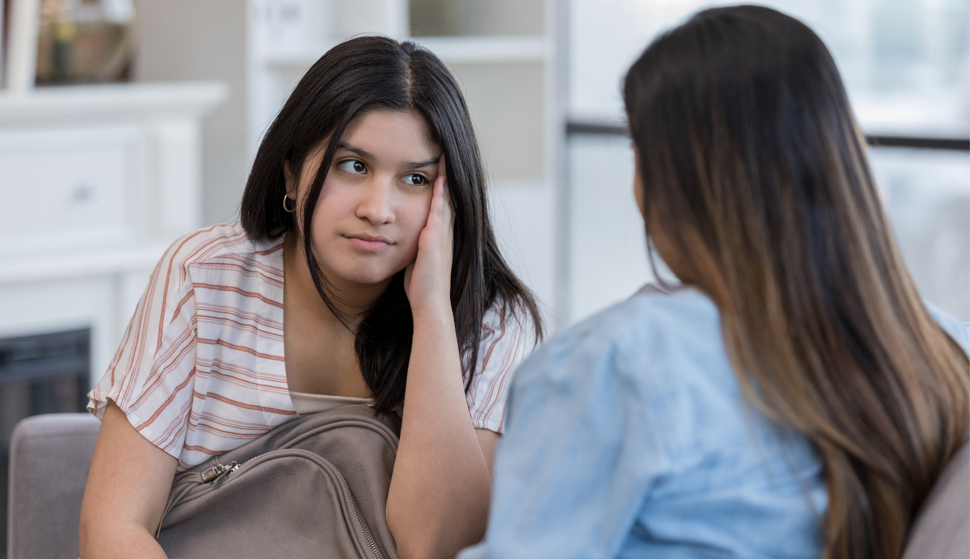 A young woman looking upset and talking to another woman.
