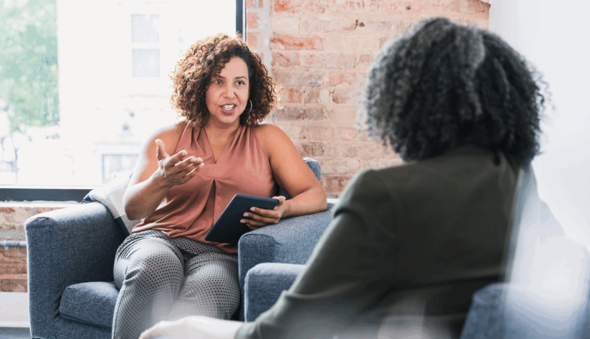 Two women sat across from one another having a conversation.