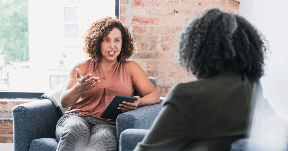 Two women sat across from one another having a conversation.