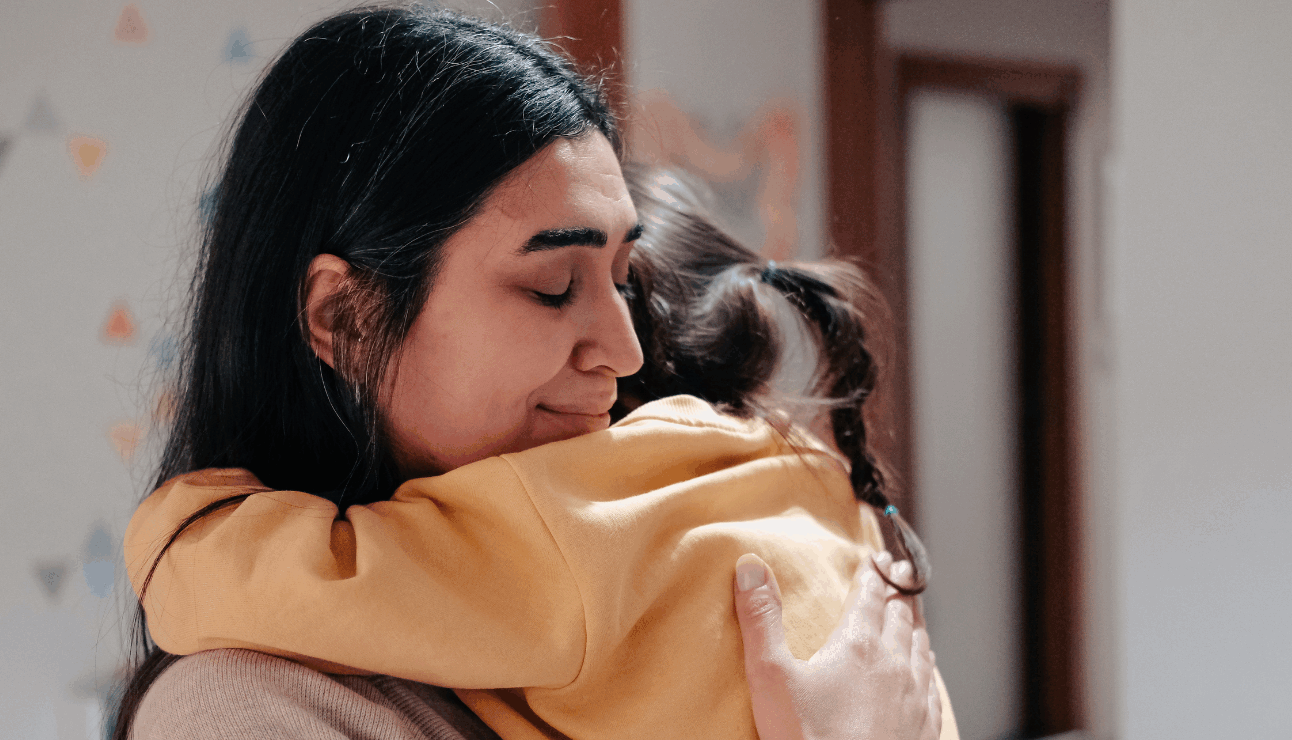 A mother hugging her young daughter.