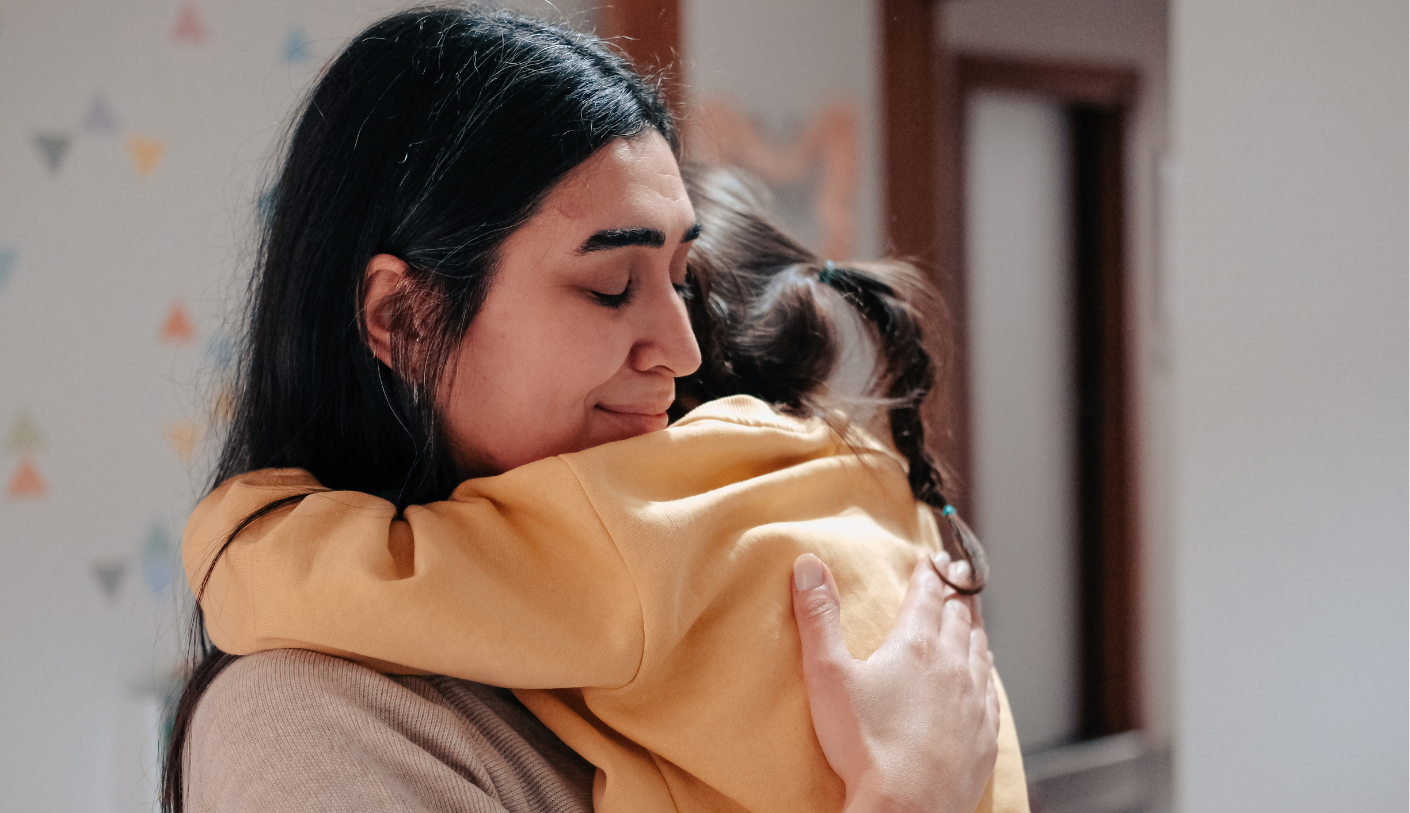 A mother hugging her young daughter.